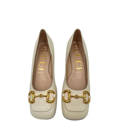 Vista superiore di un paio di décolleté Gucci in morbida pelle bianco latte, con iconico dettaglio Horsebit in metallo dorato.