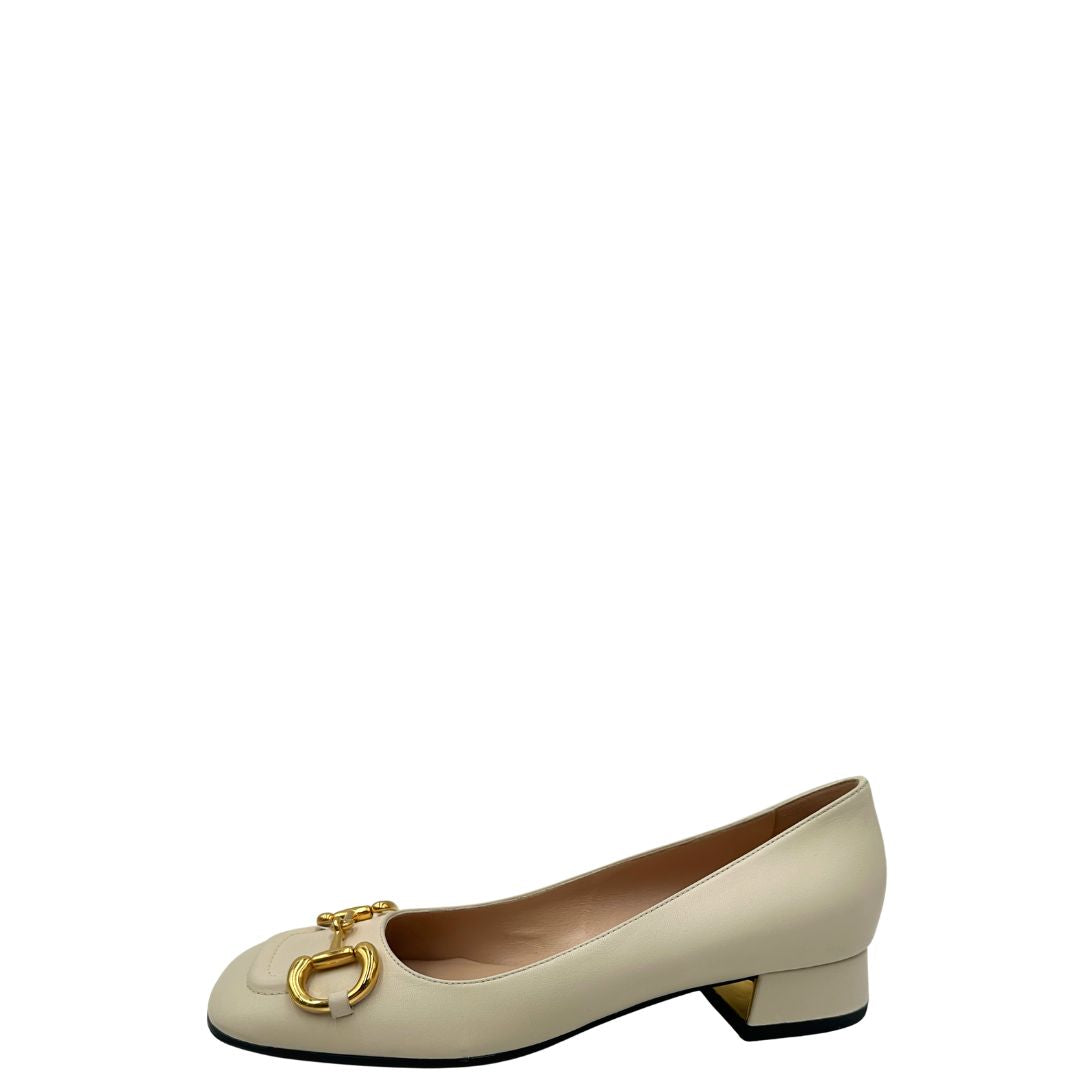 Laterale di un paio di décolleté Gucci in morbida pelle bianco latte, con iconico dettaglio Horsebit in metallo dorato.