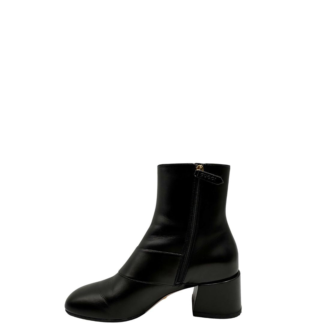 Laterale di un paio di stivaletti Gucci in pelle nera, con iconico dettaglio Soho in metallo dorato, usati, originali, second hand, in ottime condizioni.