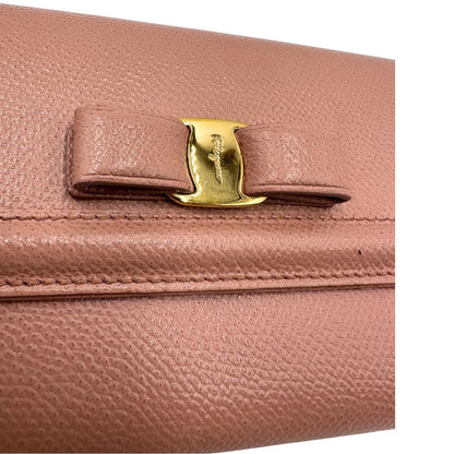 Dettaglio decorativo di un portafoglio Ferragamo in pelle rosa, dotata di un porta tessera estraibile. Iconico fiocco del brand sul front, usato, originale, second hand, in buone condizioni.