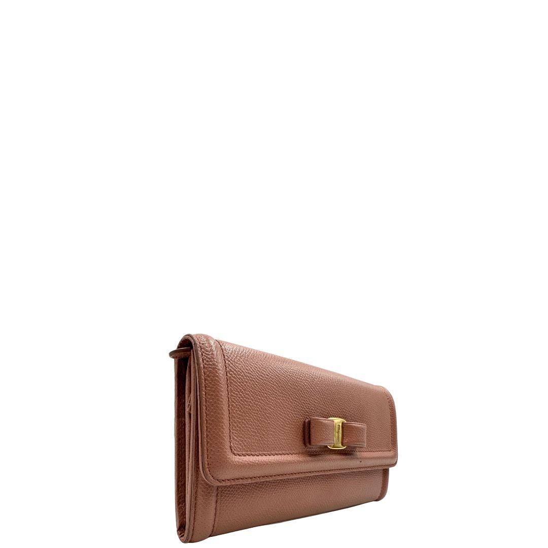 Laterale sinistro di un portafoglio Ferragamo in pelle rosa, dotata di un porta tessera estraibile. Iconico fiocco del brand sul front, usato, originale, second hand, in buone condizioni.