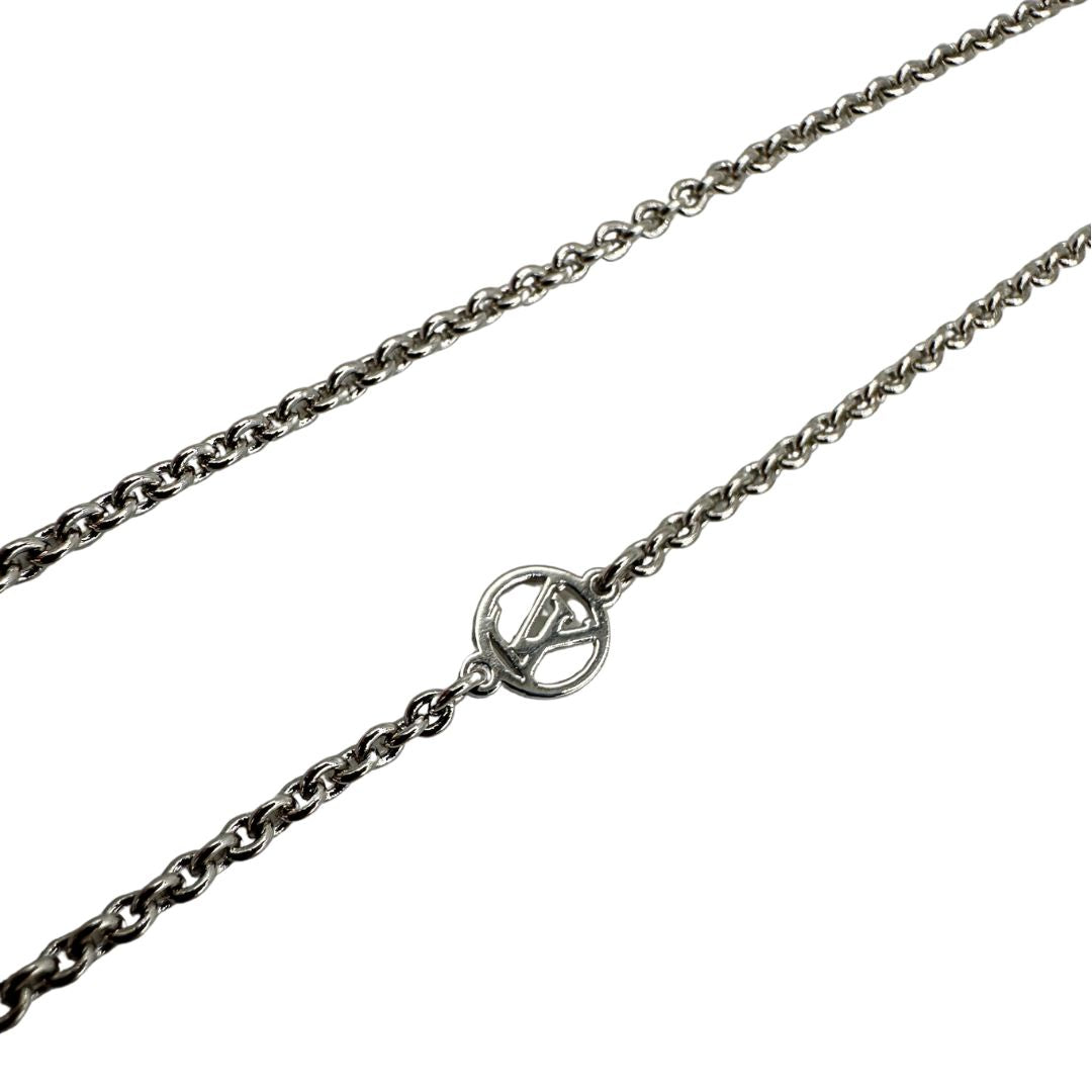 Collana Essential V Supple Louis Vuitton in metallo con finitura argentata lucida, impreziosita dal ciondolo con l'emblematica iniziale della Maison. Completata dall'iconico logo LV Circle, che impreziosisce la catenella e la chiusura con moschettone. Originale, di lusso, usata, in condizioni ottime. 