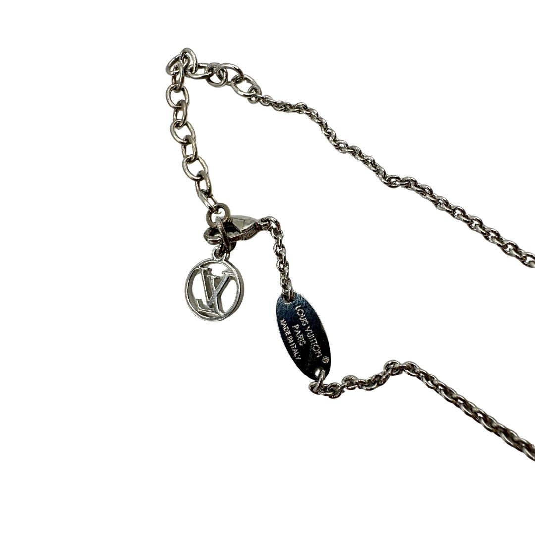 Collana Essential V Supple Louis Vuitton in metallo con finitura argentata lucida, impreziosita dal ciondolo con l'emblematica iniziale della Maison. Completata dall'iconico logo LV Circle, che impreziosisce la catenella e la chiusura con moschettone. Originale, di lusso, usata, in condizioni ottime. 