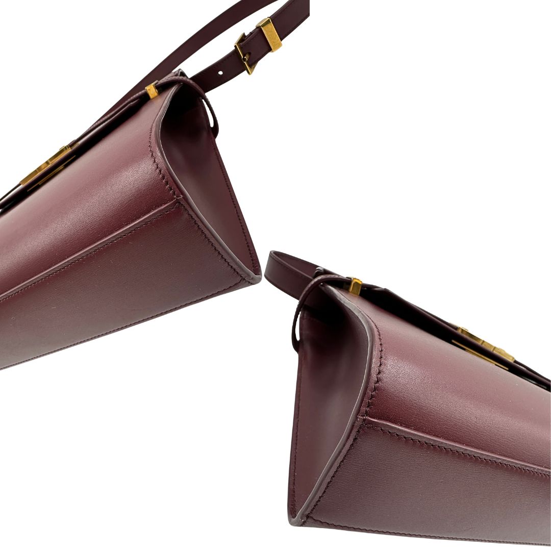 Borsa Saint Laurent Manhattan in pelle bordeaux e hardware dorato, da portare a spalla.