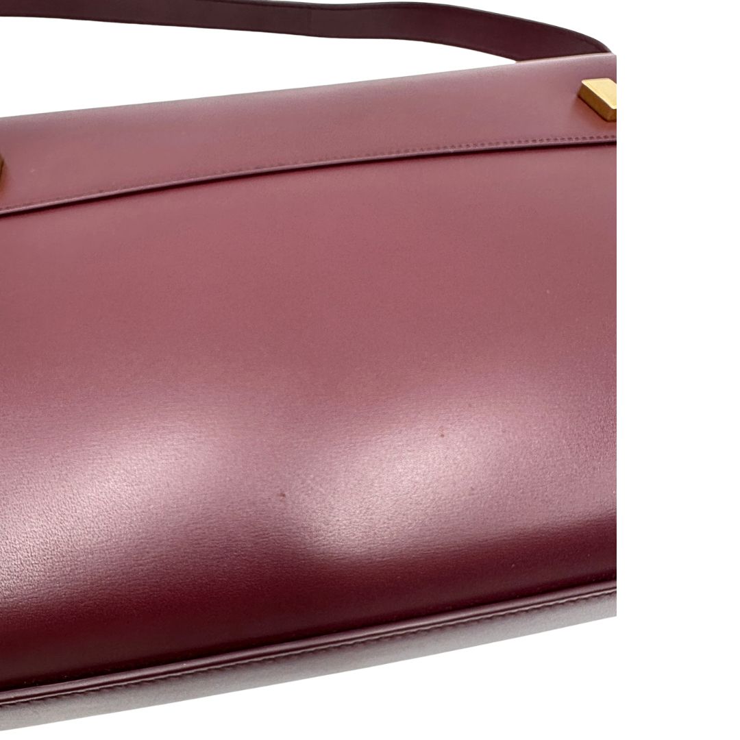Borsa Saint Laurent Manhattan in pelle bordeaux e hardware dorato, da portare a spalla.