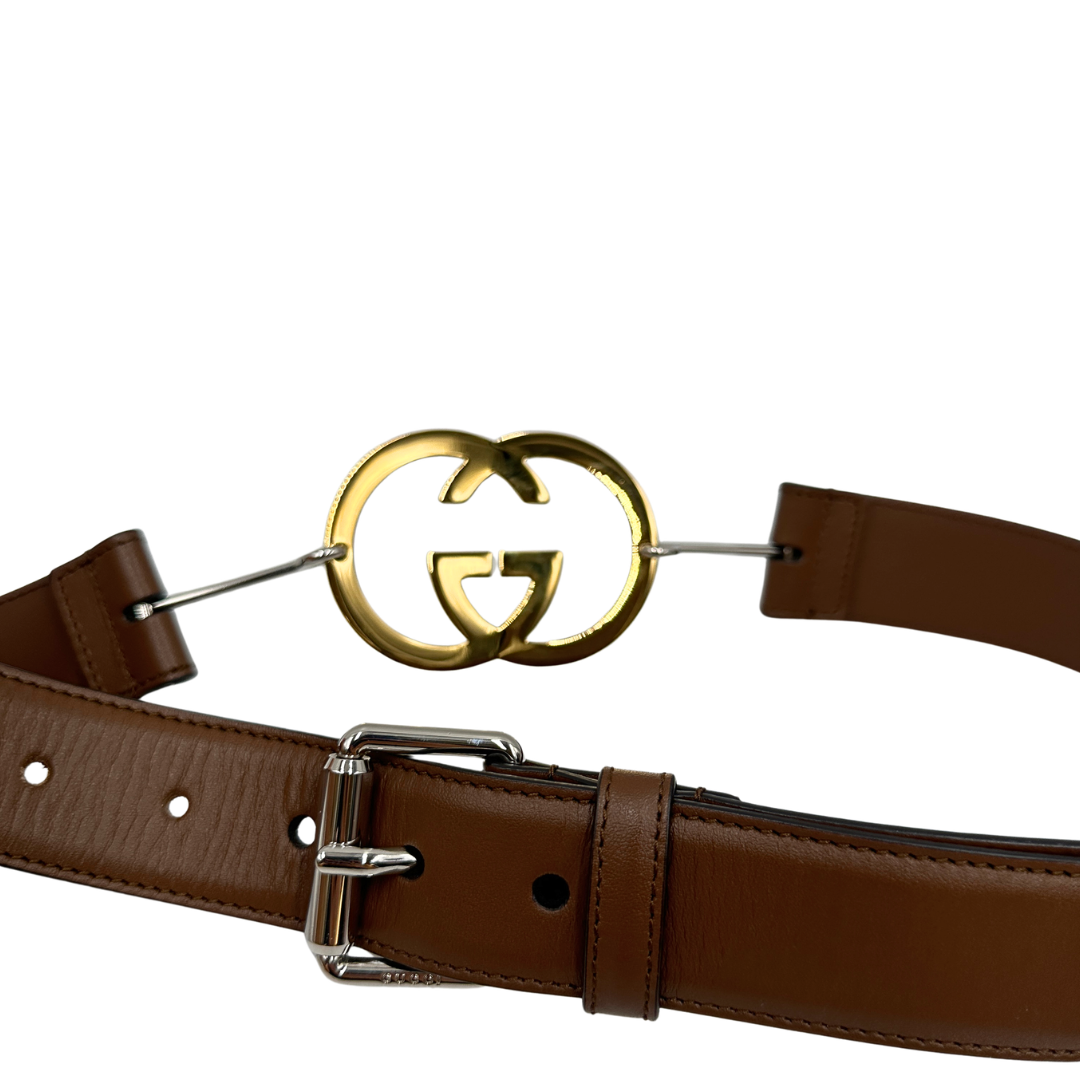 Cintura Gucci in pelle marrone con fibbia tradizionale in metallo argentato e grande elemento decorativo GG dorato inserito lungo la cintura. Originale, usata, di lusso, in ottime condizioni.