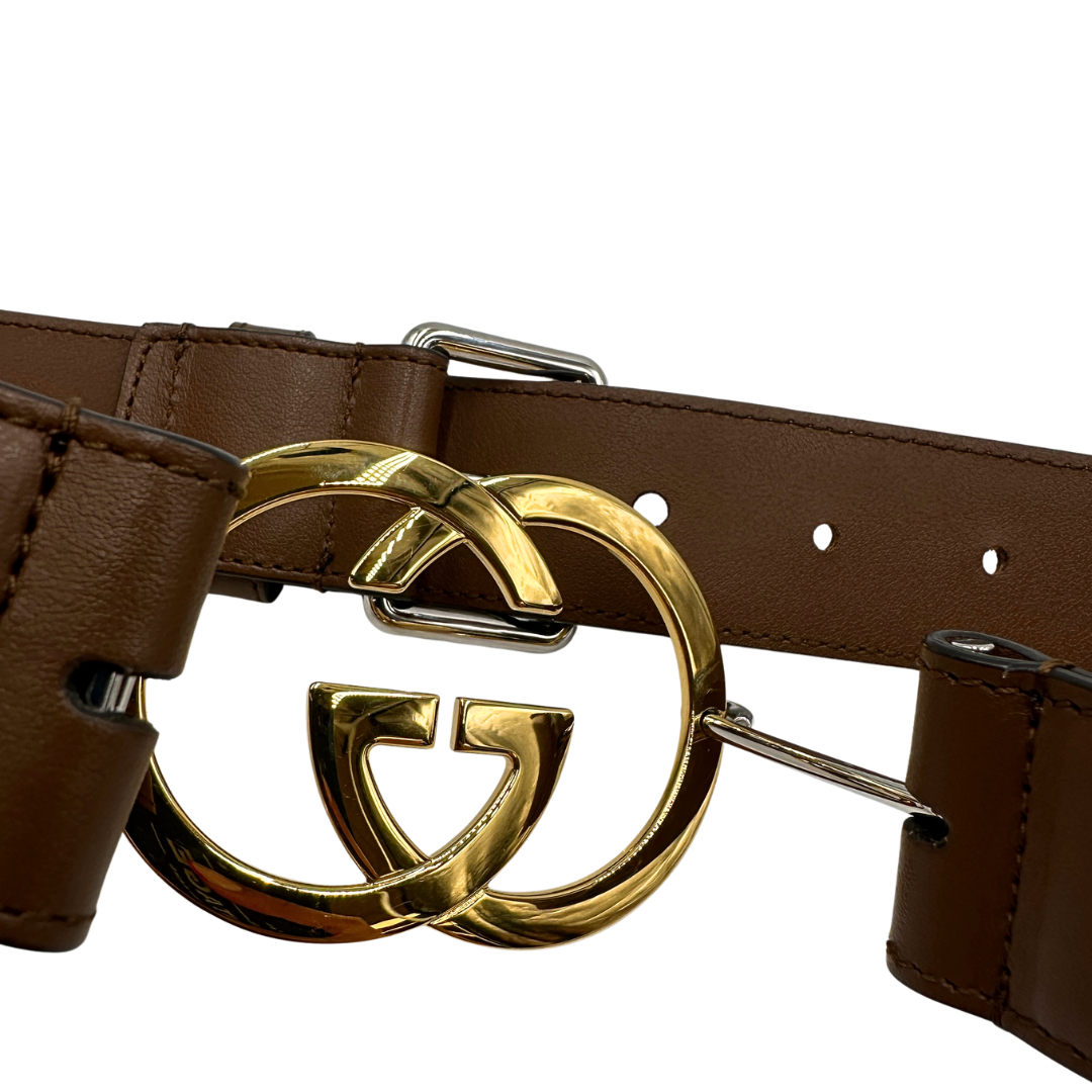 Cintura Gucci in pelle marrone con fibbia tradizionale in metallo argentato e grande elemento decorativo GG dorato inserito lungo la cintura. Originale, usata, di lusso, in ottime condizioni.