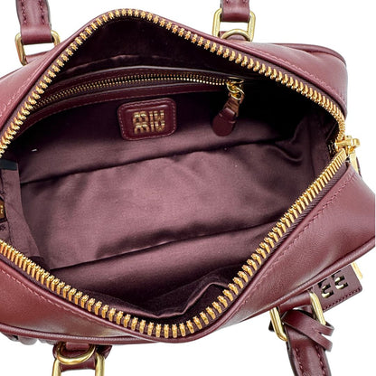 Interno, Borsa Miu Miu Arcadie realizzata in nappa matelassé bordeaux con la classica silhouette del bauletto. Da portare a mano o a tracolla. Originale, usata, di lusso, in condizioni eccellenti.