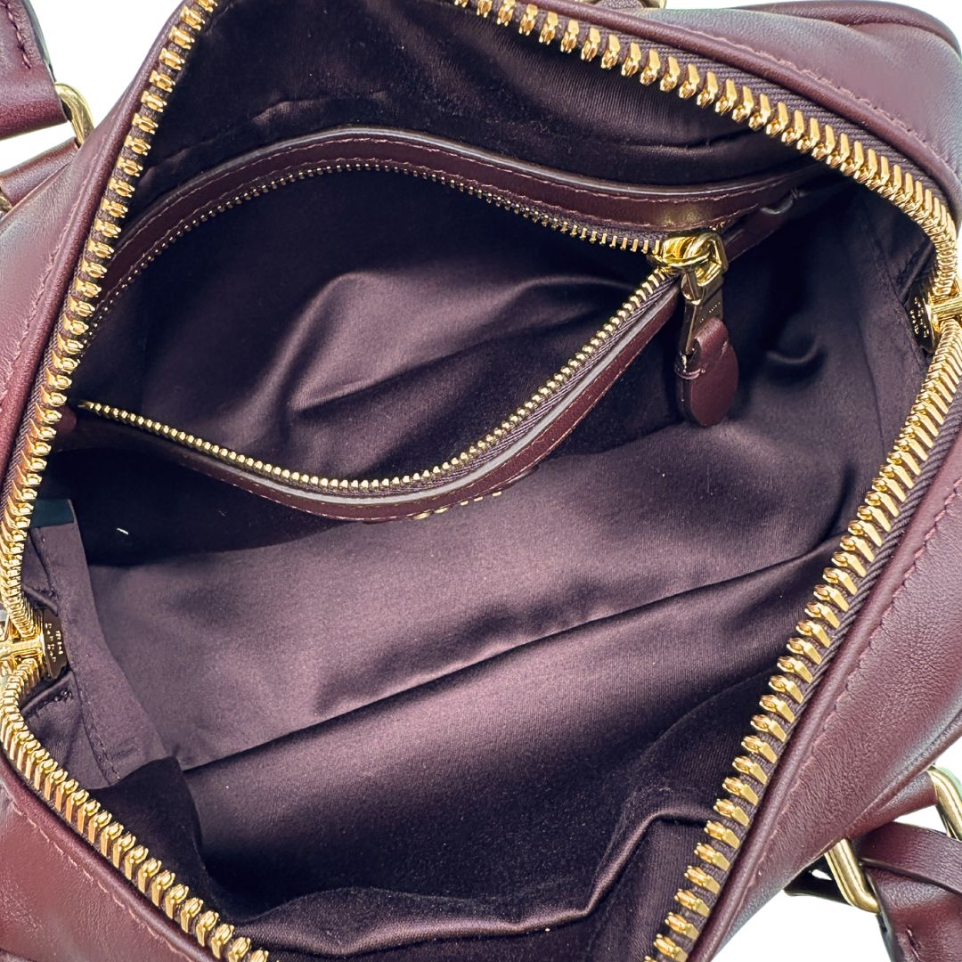 Interno, Borsa Miu Miu Arcadie realizzata in nappa matelassé bordeaux con la classica silhouette del bauletto. Da portare a mano o a tracolla. Originale, usata, di lusso, in condizioni eccellenti.