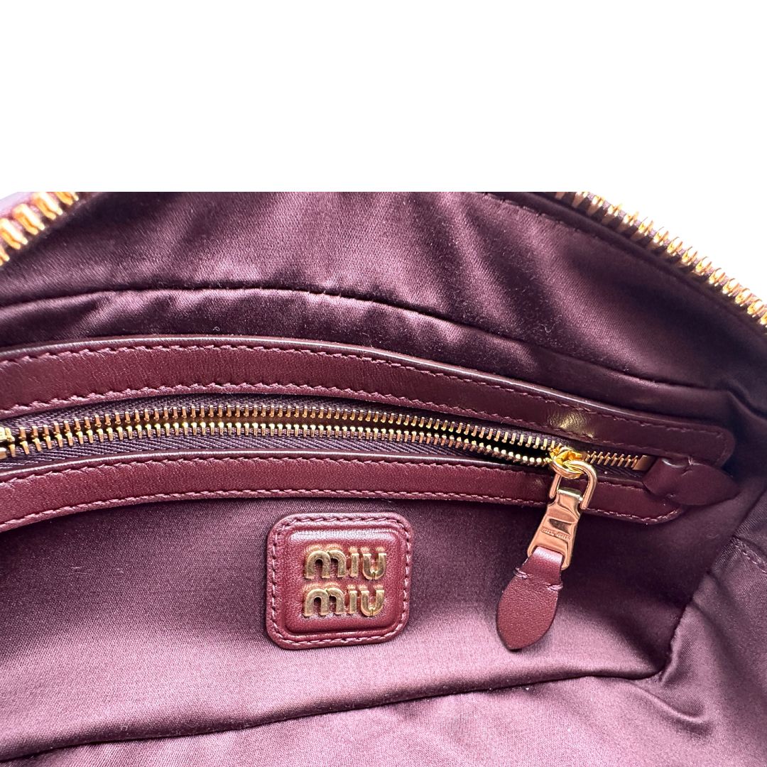 Interno, Borsa Miu Miu Arcadie realizzata in nappa matelassé bordeaux con la classica silhouette del bauletto. Da portare a mano o a tracolla. Originale, usata, di lusso, in condizioni eccellenti.