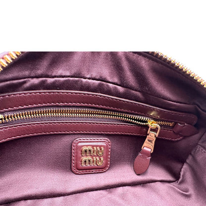 Interno, Borsa Miu Miu Arcadie realizzata in nappa matelassé bordeaux con la classica silhouette del bauletto. Da portare a mano o a tracolla. Originale, usata, di lusso, in condizioni eccellenti.