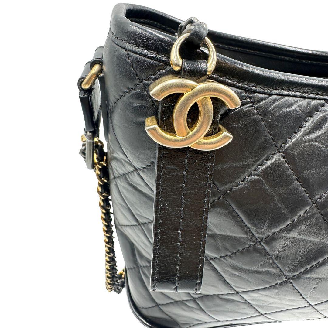 Chanel Gabrielle Hobo Bag in pelle di vitello trapuntata nera, caratterizzata da una solida base rigida inferiore, dettagli con finiture miste color oro e argento e una tracolla regolabile a catena intrecciata in pelle