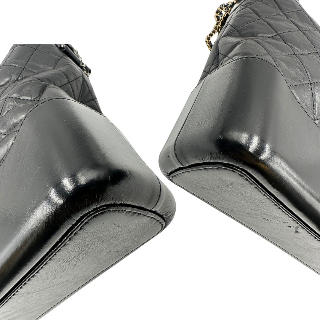 angoli Chanel Gabrielle Hobo Bag in pelle di vitello trapuntata nera, caratterizzata da una solida base rigida inferiore, dettagli con finiture miste color oro e argento e una tracolla regolabile a catena intrecciata in pelle 