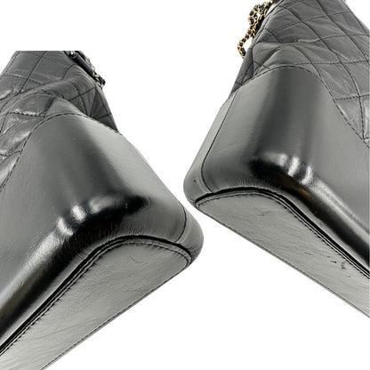 angoli Chanel Gabrielle Hobo Bag in pelle di vitello trapuntata nera, caratterizzata da una solida base rigida inferiore, dettagli con finiture miste color oro e argento e una tracolla regolabile a catena intrecciata in pelle 