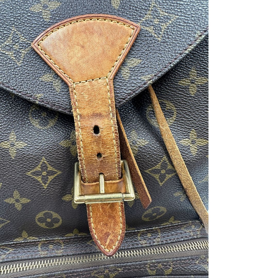Segni di utilizzo sulla vacchetta di uno zaino Montsouris GM in canvas marrone monogram con finiture in vacchetta naturale.