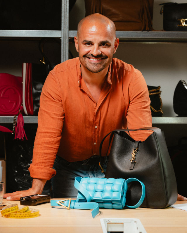 Uomo sorridente seduto al banco da lavoro con una borsa e accessori per la cura del prodotto.