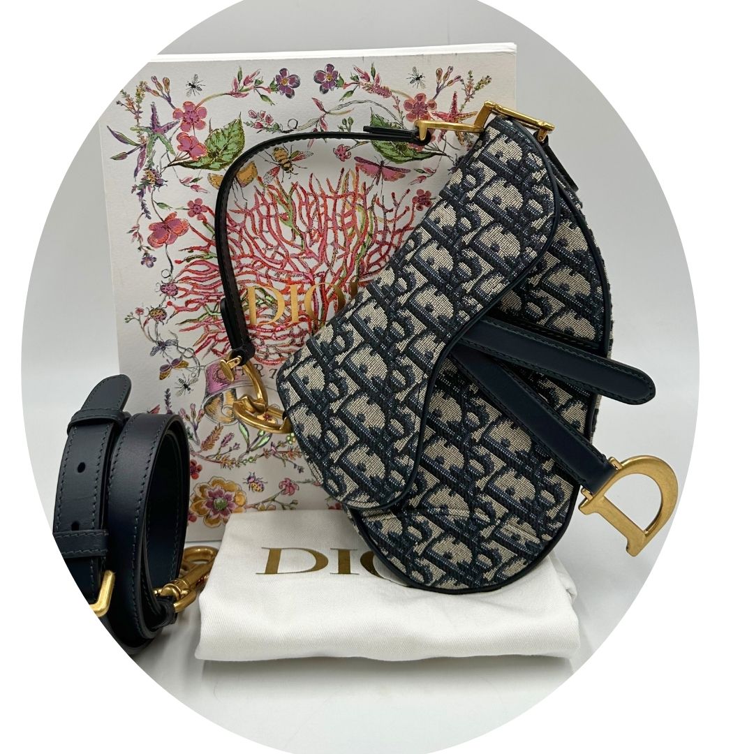Borsa Saddle Dior in tessuto beige con trama Dior Oblique nera e blu, finiture in pelle blu notte e parti metalliche dorate. Munita di manico singolo e tracolla regolabile, e amovibile. Completa di corredo. Originale, usato, condizioni ottime. 