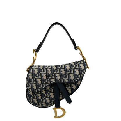 Borsa Saddle Dior in tessuto beige con trama Dior Oblique nera e blu, finiture in pelle blu notte e parti metalliche dorate. Munita di manico singolo e tracolla regolabile, e amovibile. Completa di corredo. Originale, usato, condizioni ottime. 