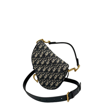 Borsa Saddle Dior in tessuto beige con trama Dior Oblique nera e blu, finiture in pelle blu notte e parti metalliche dorate. Munita di manico singolo e tracolla regolabile, e amovibile. Completa di corredo. Originale, usato, condizioni ottime. 