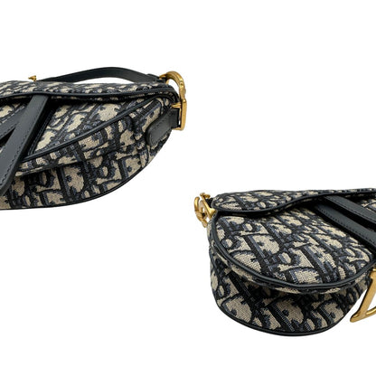 Borsa Saddle Dior in tessuto beige con trama Dior Oblique nera e blu, finiture in pelle blu notte e parti metalliche dorate. Munita di manico singolo e tracolla regolabile, e amovibile. Completa di corredo. Originale, usato, condizioni ottime. 