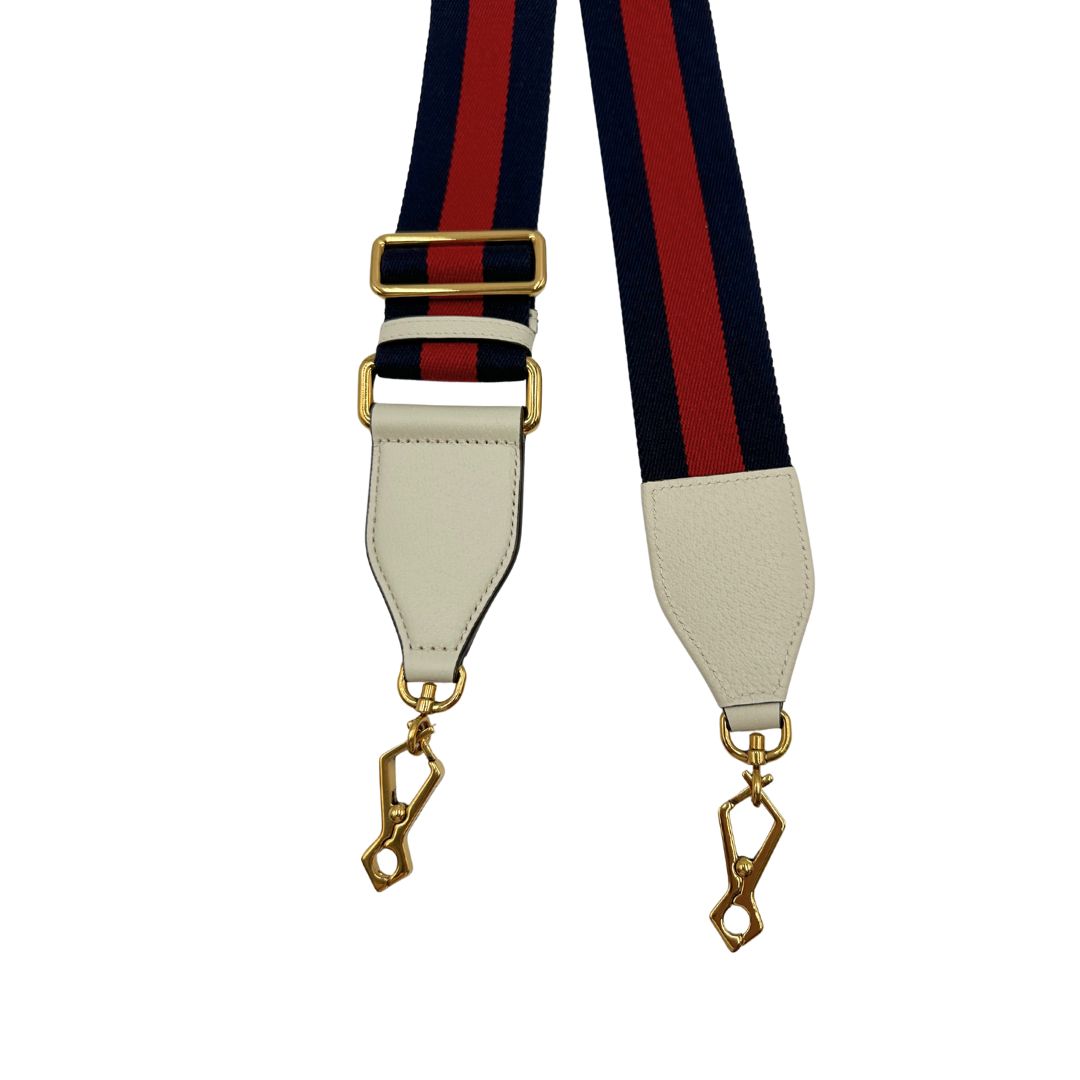 Tracolla Gucci in tessuto con iconica striscia web rossa e blu, rifinita con parti in pelle bianche e parti metalliche dorate.&nbsp;