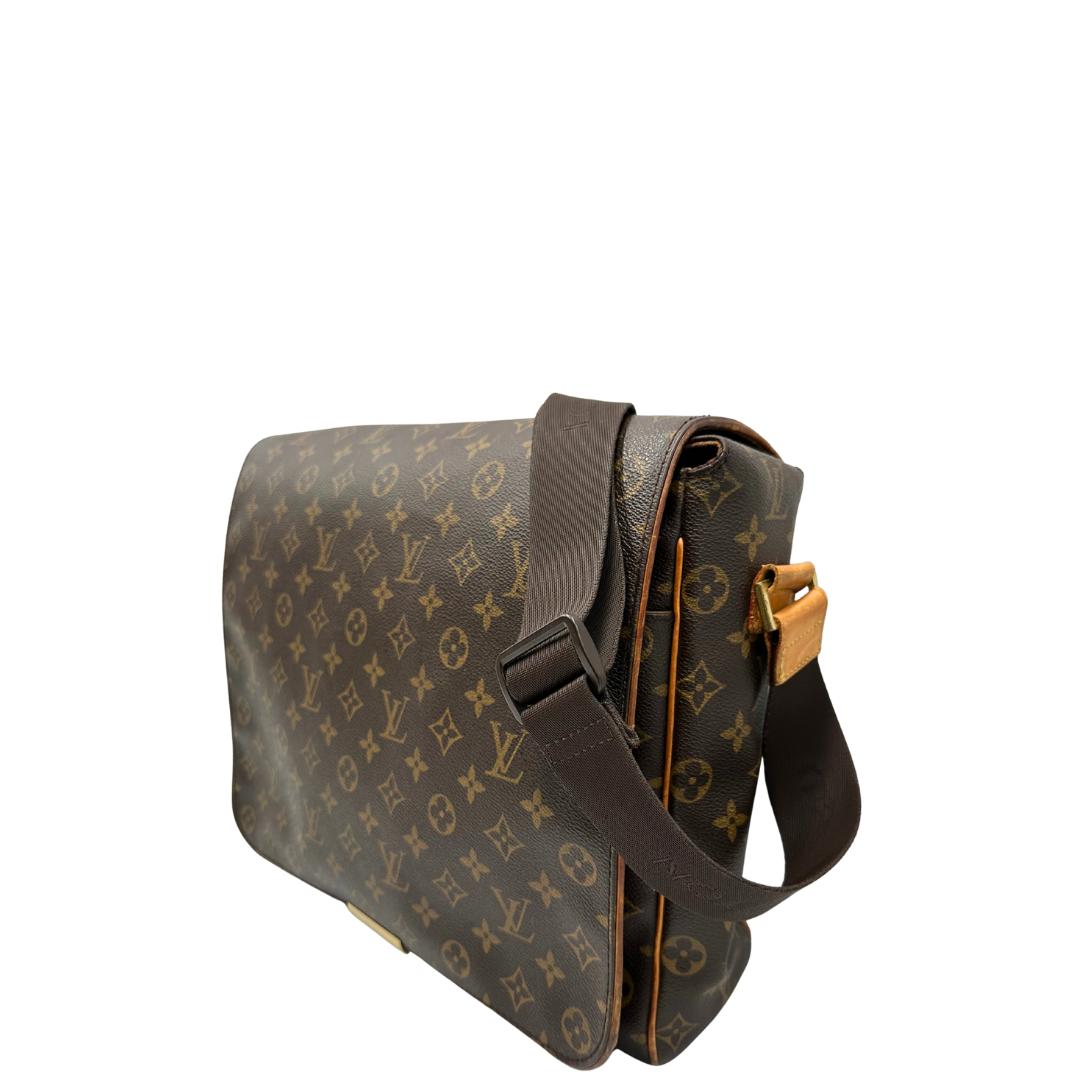 Lato sinistro di una Cartella Louis Vuitton in canvas marrone monogram con finiture in vacchetta naturale e parti metalliche dorate. Munita di una tracolla in tessuto regolabile. Originale, usata, di lusso, in ottime condizioni