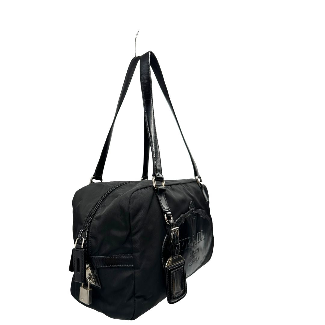 laterale della Borsa Prada in nylon nero con finiture in pelle tono su tono e parti metalliche argentate; munita di doppi manici e accessorio porta address, di lusso, originale, ottime condizioni, usata. 