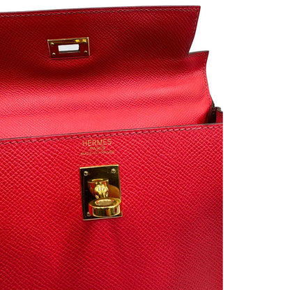 Apertura di una borsa Hermès caratterizzata da un corpo in pelle Epsom color Rouge Casaque, un manico superiore e una tracolla piatta rimovibile e non regolabile; da portare a mano o a tracolla. Completa di full set.