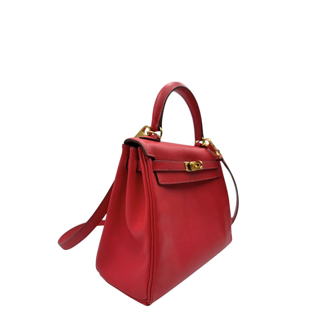 Laterale sinistro di una borsa Hermès caratterizzata da un corpo in pelle Epsom color Rouge Casaque, un manico superiore e una tracolla piatta rimovibile e non regolabile; da portare a mano o a tracolla. Completa di full set.