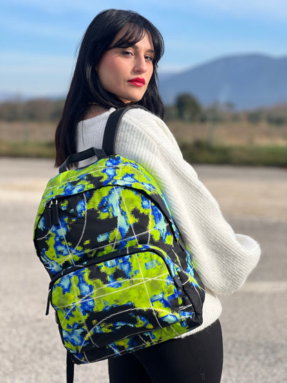 Ragazza che indossa uno zaino Prada Radar in nylon tecnico con chiusura a zip. Design caratterizzato da stampa grafica multicolor effetto radar. Struttura con ampio scomparto principale, tasca frontale a zip e tasca interna con zip. Spallacci regolabili con imbottitura e pannello posteriore traspirante in mesh per un maggiore comfort. Manico superiore in pelle nera saffiano. Dettagli con logo triangolo Prada smaltato applicato sul fronte.