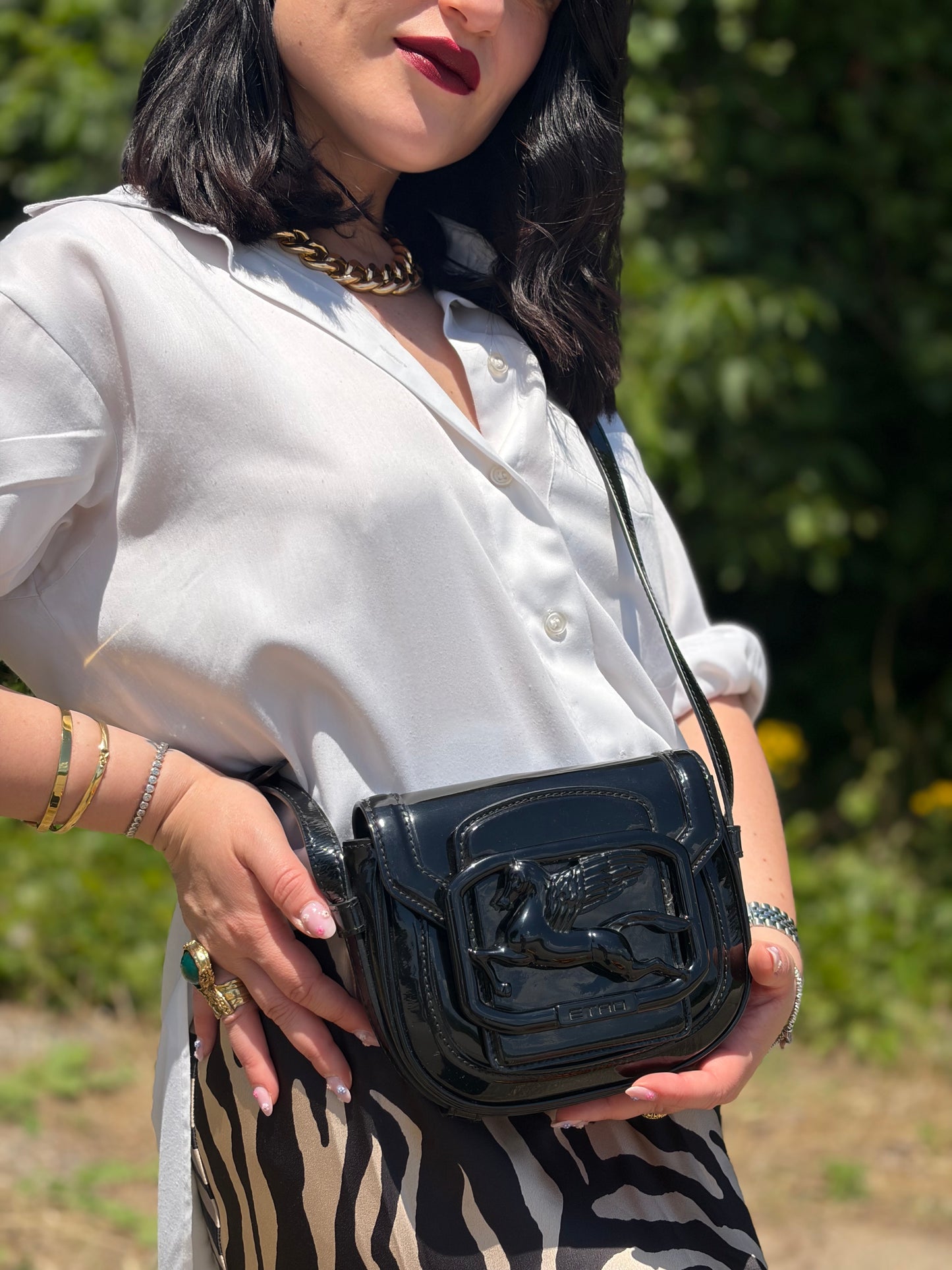 Indossata, Borsa Etro in pelle verniciata nera dal design elegante e compatto, con iconico logo Pegaso in rilievo tono su tono. Indossabile a tracolla.