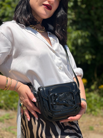 Indossata, Borsa Etro in pelle verniciata nera dal design elegante e compatto, con iconico logo Pegaso in rilievo tono su tono. Indossabile a tracolla.