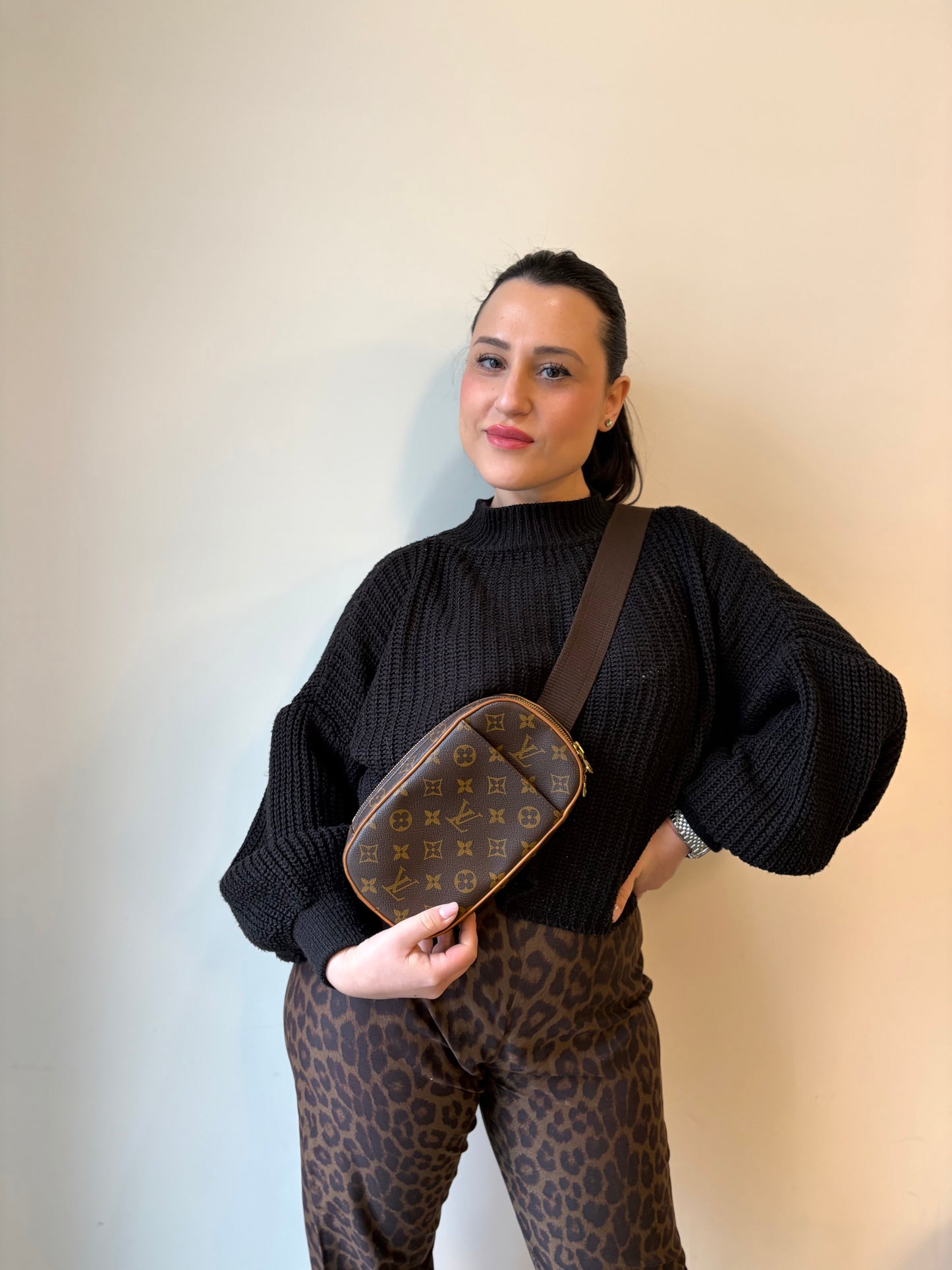 Ragazza che indossa una borsa Louis Vuitton in canvas marrone monogram con finiture in vacchetta naturale e tracolla in tessuto marrone regolabile. Dotata di dustbag.