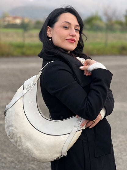 Ragazza che indossa una borsa Gucci in tessuto avorio GG con parti in pelle bianco gesso e parti metalliche argentate. Indossabile a spalla.