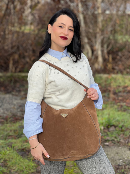 indossata a spalla  Borsa Prada in pelle scamosciata marrone con parti metalliche dorate; munita di un manico singolo regolabile; indossabile a spalla o a tracolla. Completa di dustbag, di lusso, originale, ottime condizioni, usata. 