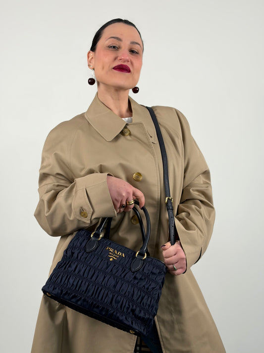 Ragazza che indossa una tote Prada goffrata in tessuto blu notte, dotata di tracolla, usata, originale, second hand, in condizioni eccellenti.