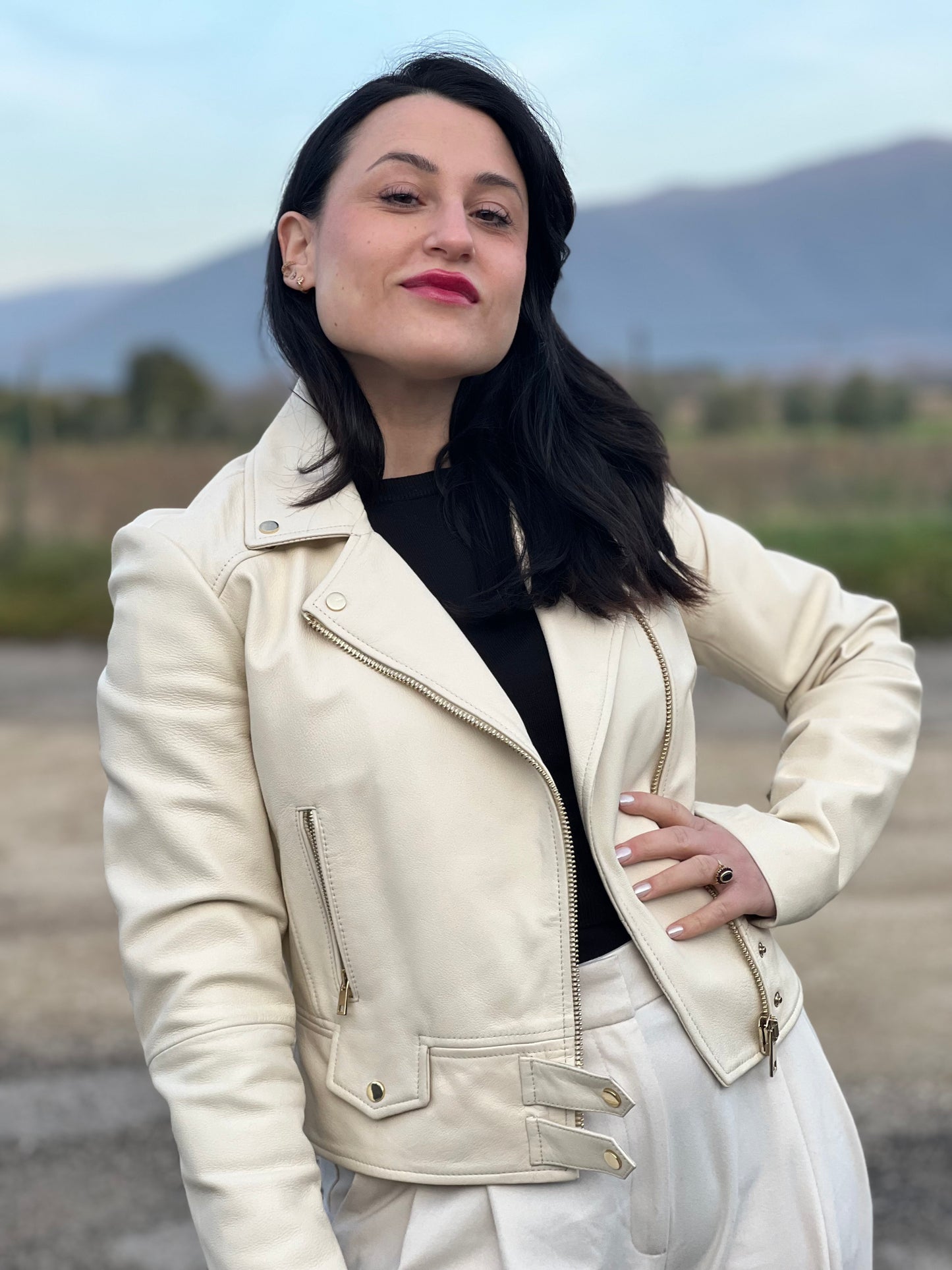 Ragazza che indossa una giacca in 100% pelle Pinko bianco latte, con parti metalliche dorate, taglia 40.