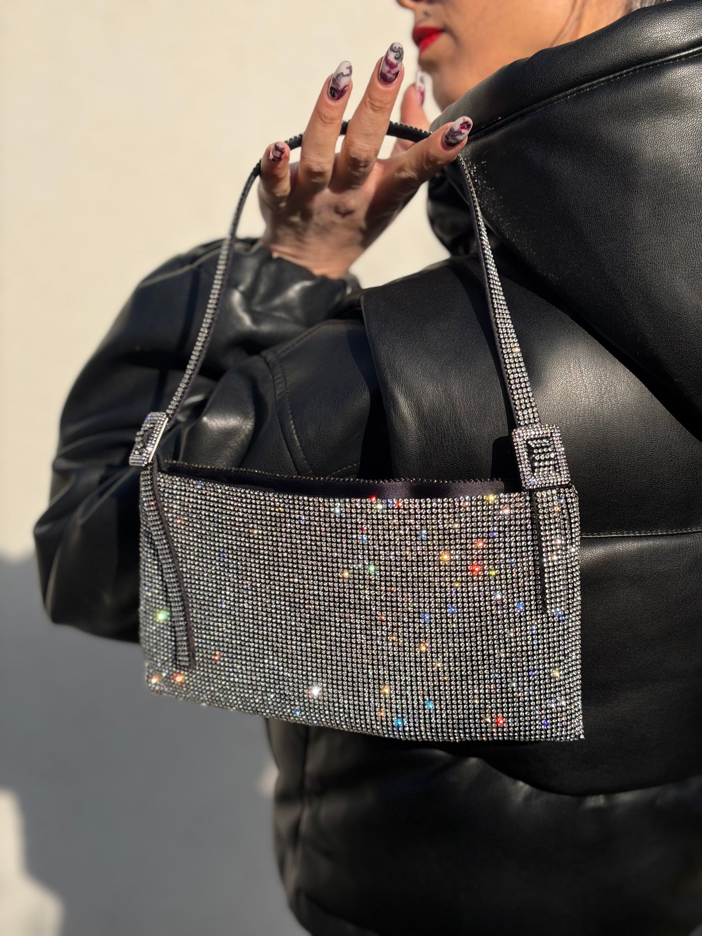 Ragazza che indossa una borsa Benedetta Bruzziches in tessuto ricoperto da strass multicolore; munita di un manico singolo con fibbie laterali, indossabile a spalla. Completa di dustbag e scatola.