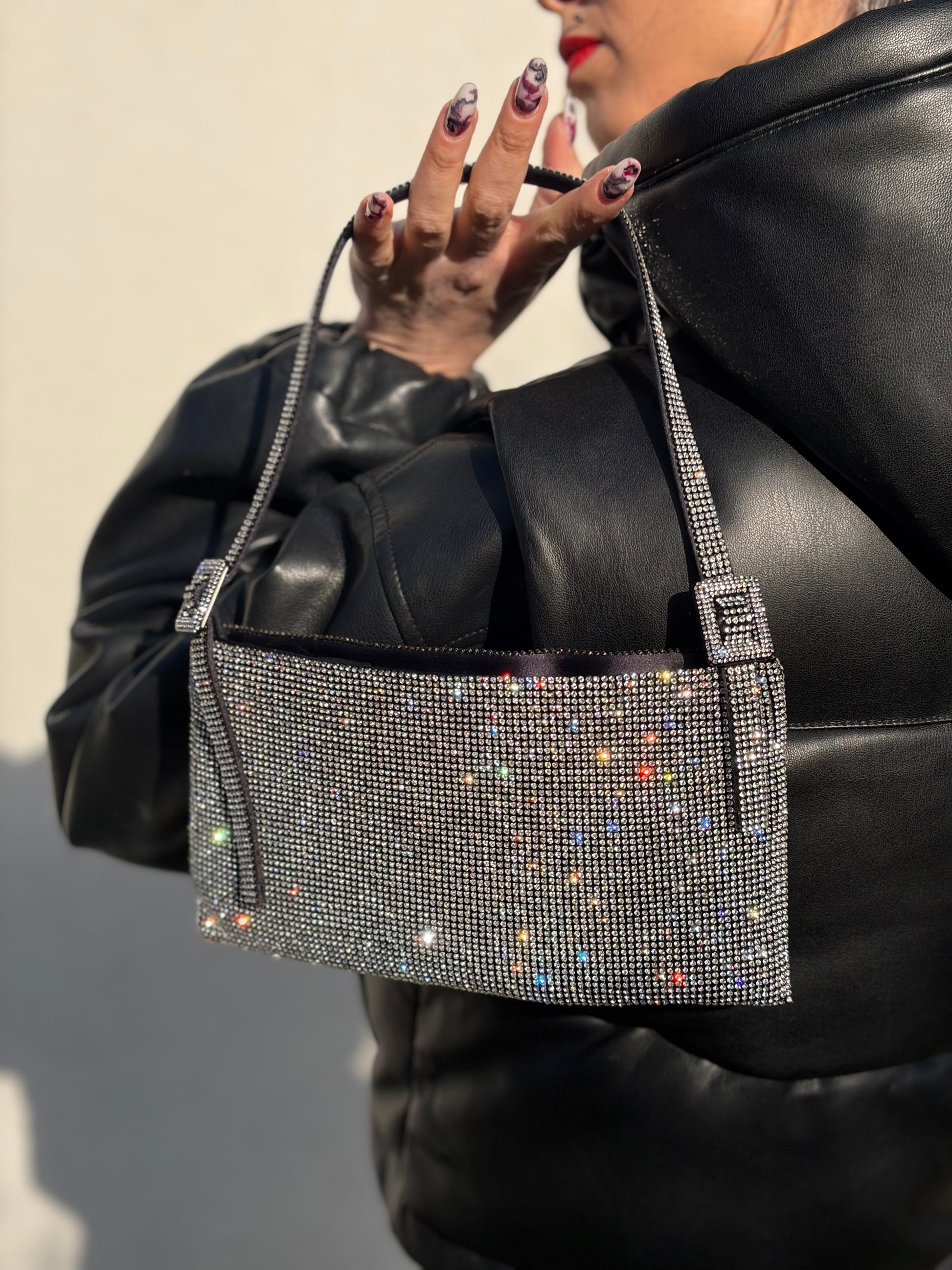 Ragazza che indossa una borsa Benedetta Bruzziches in tessuto ricoperto da strass multicolore; munita di un manico singolo con fibbie laterali, indossabile a spalla. Completa di dustbag e scatola.
