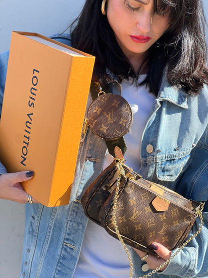 Ragazza che indossa una Multi Pochette Accessoires Louis Vuitton in canvas marrone monogram con dettagli in vacchetta naturale, manico in catena dorata e tracolla in tessuto Jacquard verde kaki. Dotata del classico mini portamonete rotondo, rimovibile. Completa di corredo.