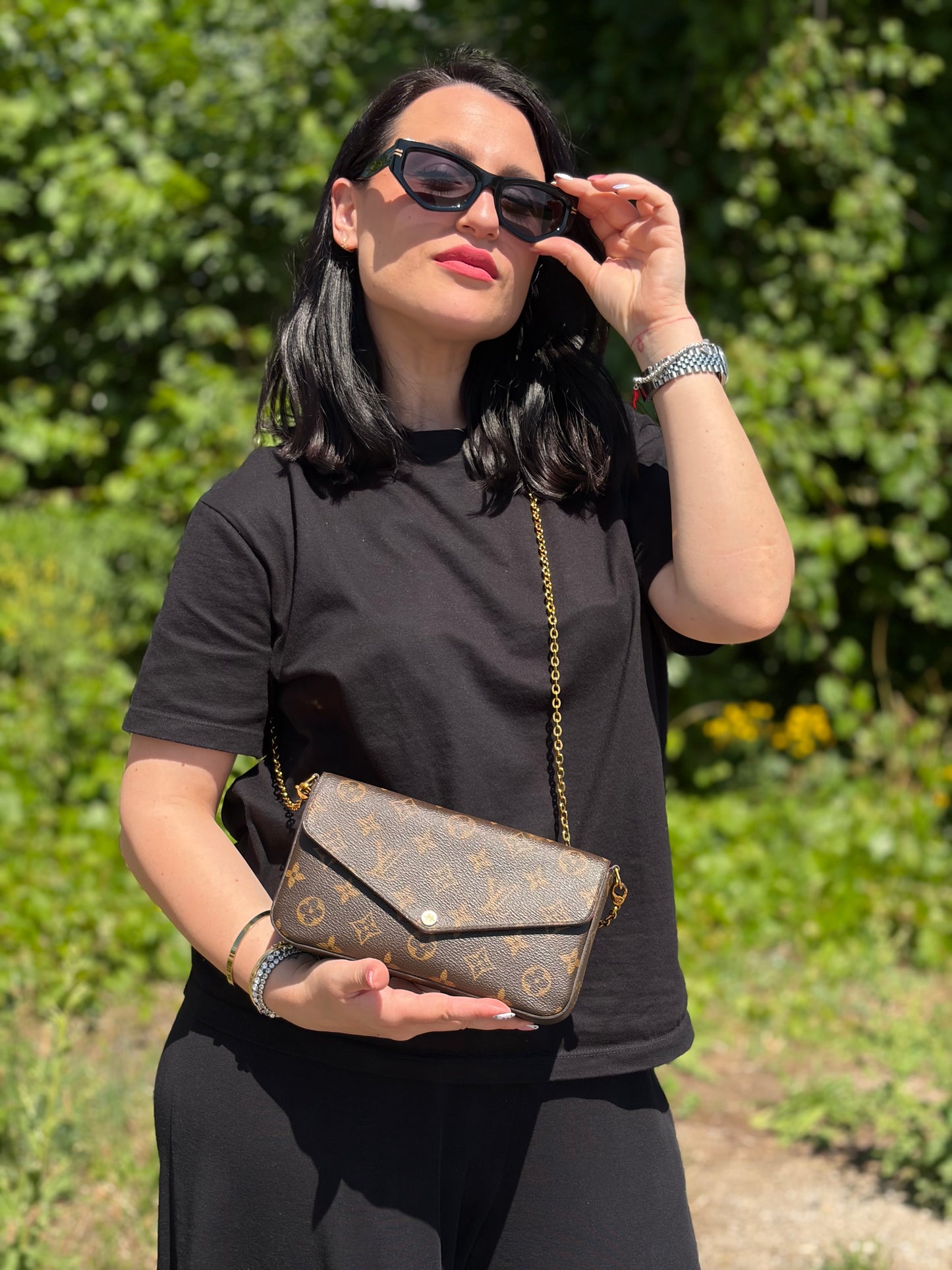 Ragazza che indossa una tracolla Louis Vuitton in canvas marrone monogram ed amaranto, con parti metalliche dorate. Munita di una tracolla in catena amovibile, ma non regolabile e di accessori estraibili portamonete e portacarte, usata, originale, second hand, in ottime condizioni.