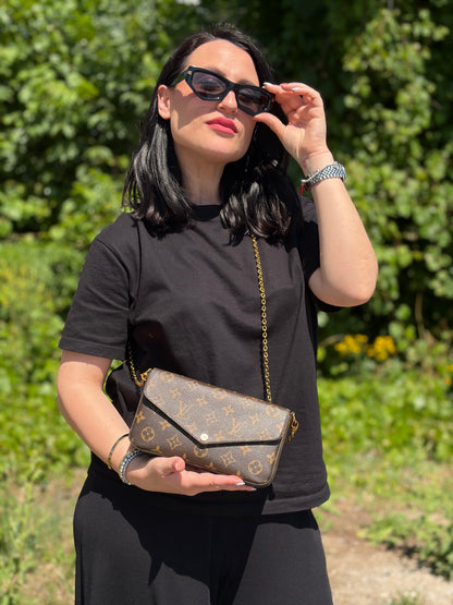 Ragazza che indossa una tracolla Louis Vuitton in canvas marrone monogram ed amaranto, con parti metalliche dorate. Munita di una tracolla in catena amovibile, ma non regolabile e di accessori estraibili portamonete e portacarte, usata, originale, second hand, in ottime condizioni.