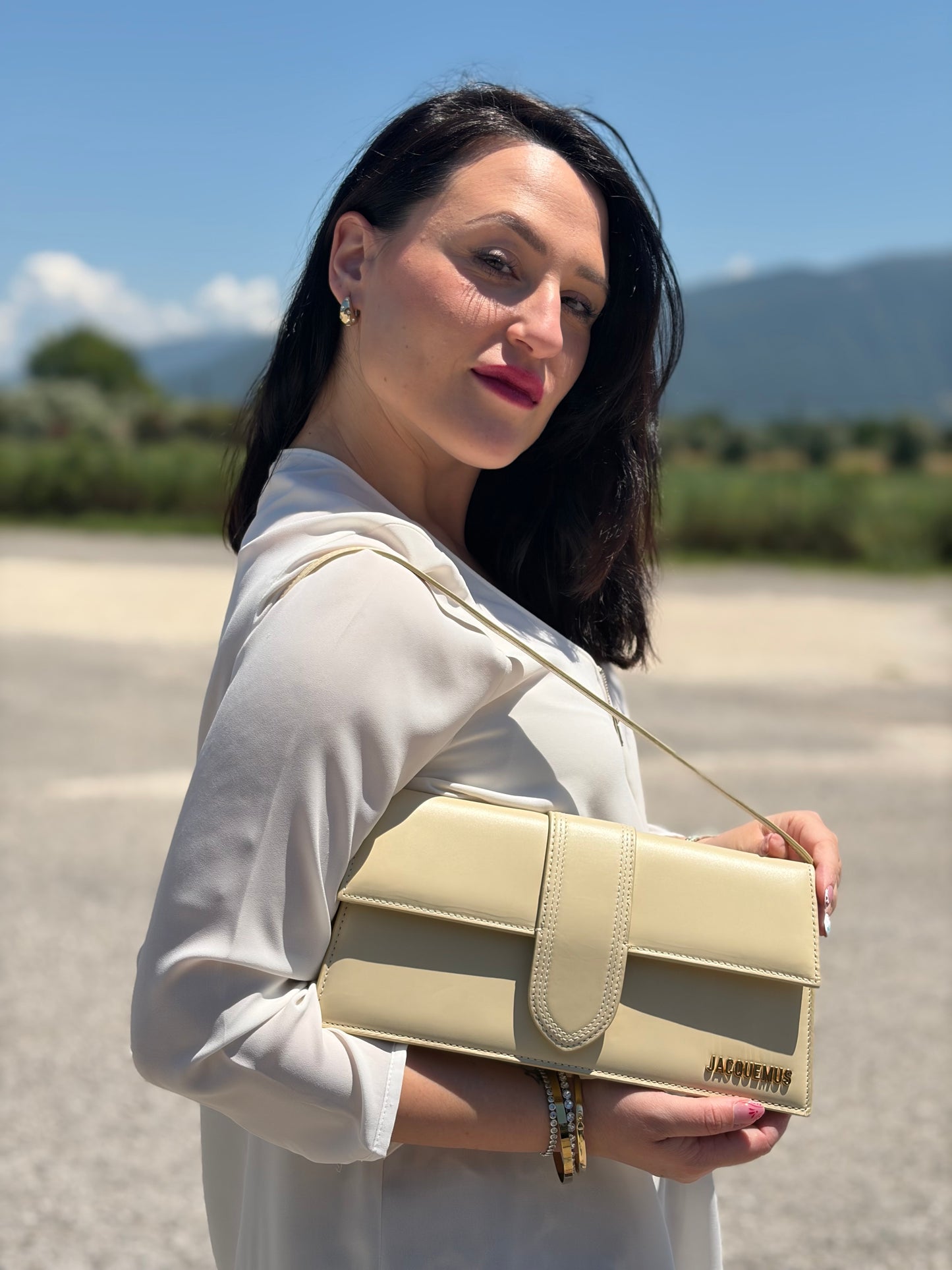 Ragazza che indossa una borsa Jacquemus nella versione Le Bambino Long in pelle beige, usata, originale, second hand, in ottime condizioni.