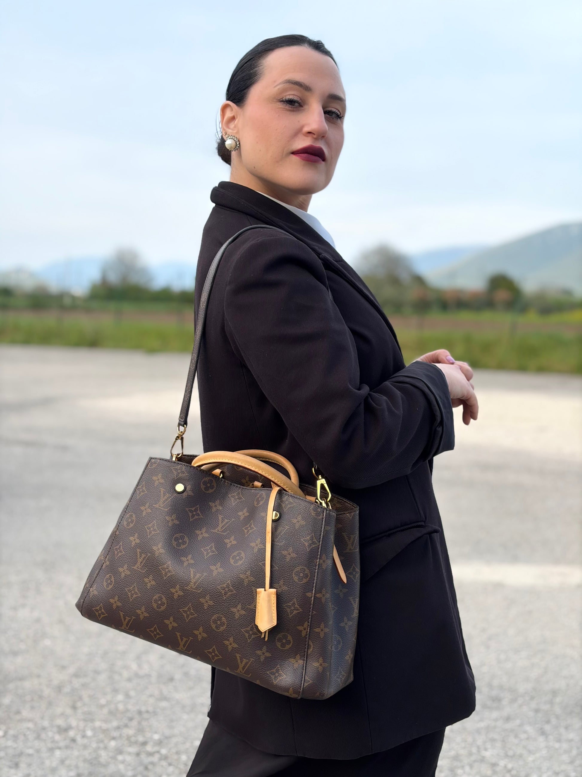 Indossata, Borsa Louis Vuitton Montaigne nella versione media in canvas marrone e hardware dorato, indossabile a mano oppure a spalla. Originale, usata, di lusso, in ottime condizioni.