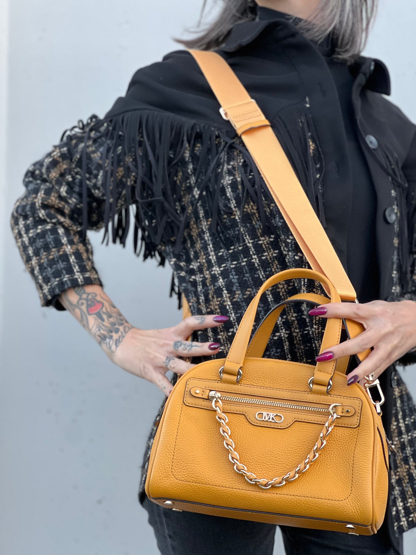 Ragazza che indossa una borsa Michael Kors in pelle martellata giallo girasole, con metalleria dorata. Munita di tracolla in tessuto regolabile ed amovibile. Completa di dustbag e cartellini.