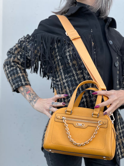 Ragazza che indossa una borsa Michael Kors in pelle martellata giallo girasole, con metalleria dorata. Munita di tracolla in tessuto regolabile ed amovibile. Completa di dustbag e cartellini.