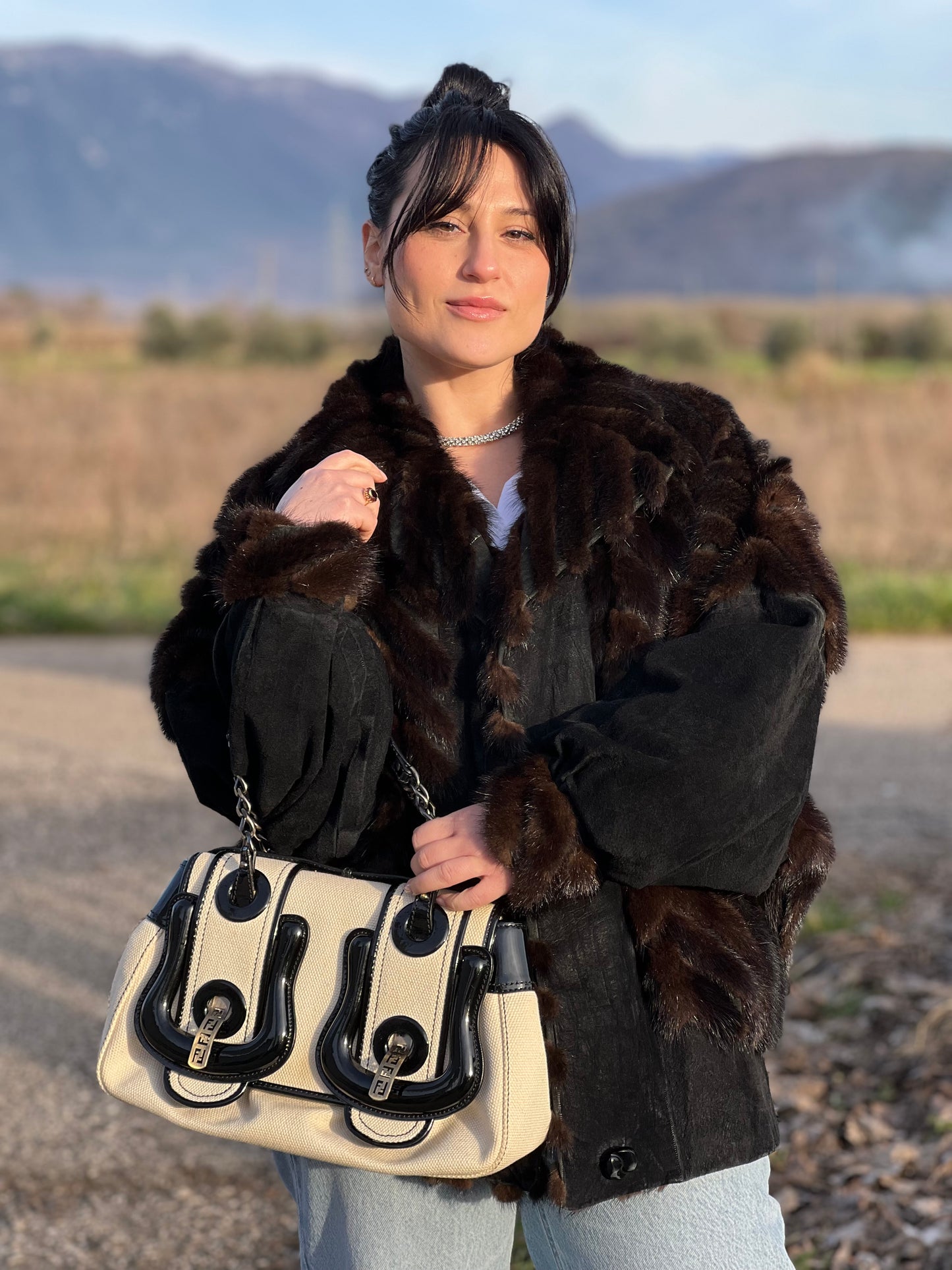 indossata della  Borsa Fendi in tessuto bianco avorio con finiture in pelle lucida nera e parti metalliche color ottone; munita di doppi manici in catena e pelle, indossabile a spalla. Completa di dustbag, di lusso, usata, ottime condizioni, originale.