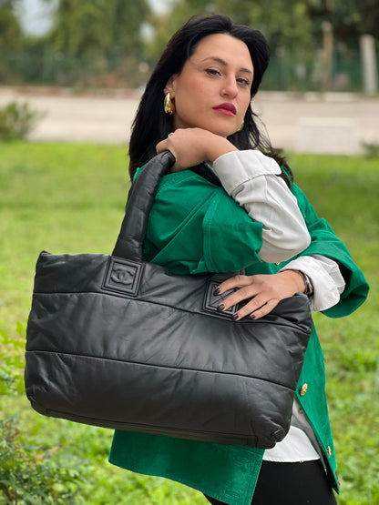 Ragazza che indossa una borsa Chanel in pelle effetto imbottito nera, con metalleria argentata. Da indossare a spalla.