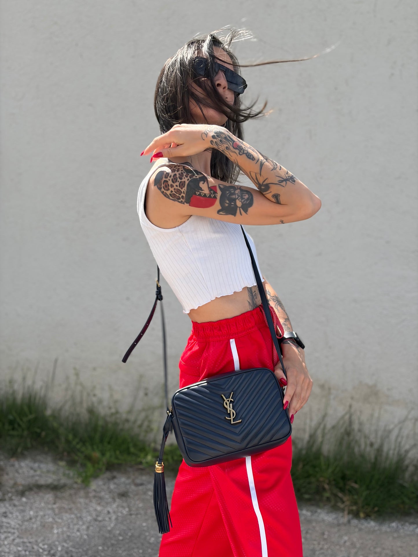 Ragazza che indossa una borsa Saint Laurent blu navy con iconico logo centrale YSL, caratterizzata da impunture trapuntate ad “y” e nappa decorativa, usata, originale, second hand, in ottime condizioni.