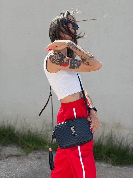 Ragazza che indossa una borsa Saint Laurent blu navy con iconico logo centrale YSL, caratterizzata da impunture trapuntate ad “y” e nappa decorativa, usata, originale, second hand, in ottime condizioni.